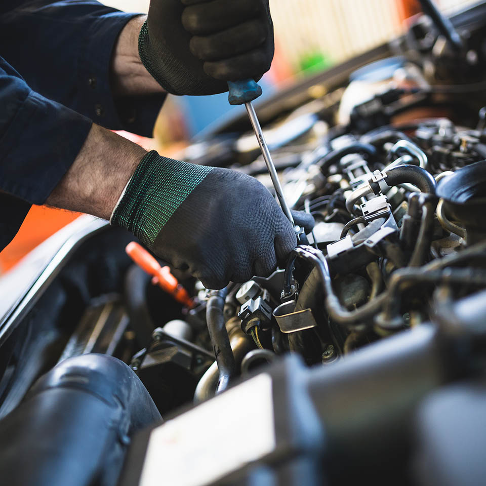 Close up hands of unrecognizable mechanic doing car service and maintenance.