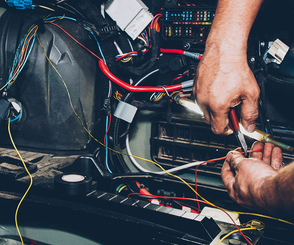 Mechanic electrician checking repairing upgrading wiring. Auto service workshop. Regular preventive car maintenance.