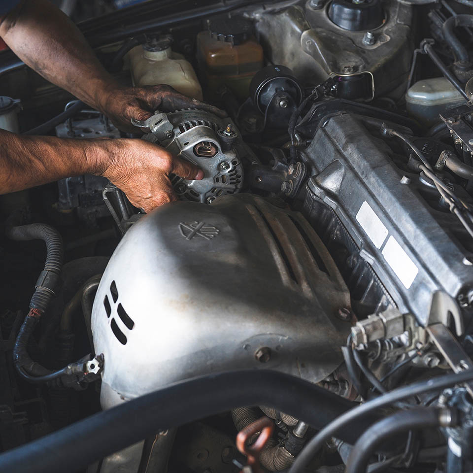 Car mechanic replacing a car Alternator.